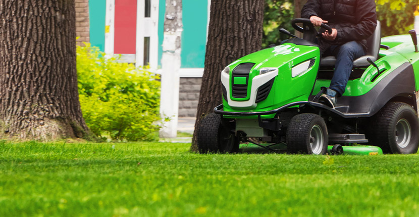 mowing the lawn with a green riding mower