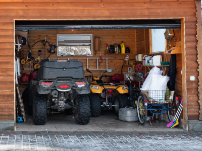 An open garage with 2 four-wheelers and other items