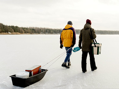 Two people walking across ice with fishing gear