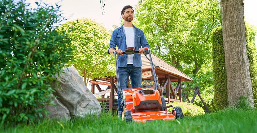 Person pushing an orange lawn mower