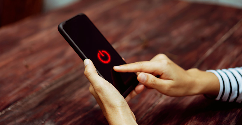 Person holding an iPhone with red power icon on the screen