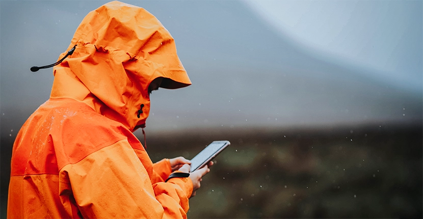 Person wearing a raincoat while looking at their phone