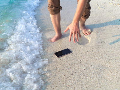 Picking up a phone that fell on the sand near the water