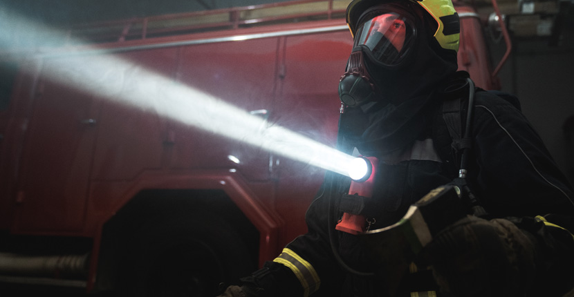Firefighter in full gear holding a high-powered flashlight