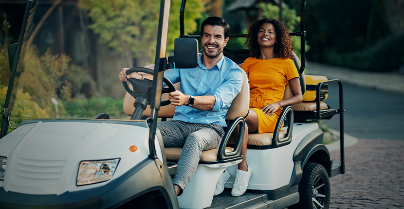 Two people riding in a golf cart