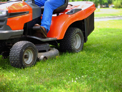 Angled side view of an orange and black riding lawn mower