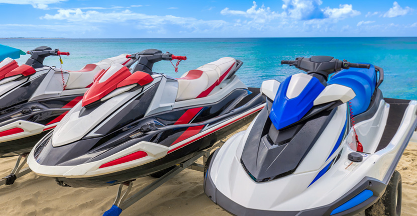 Three jet skis sitting on a trailer at the beach