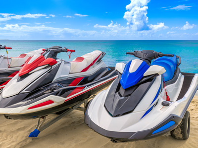 Three jet skis sitting on a trailer at the beach