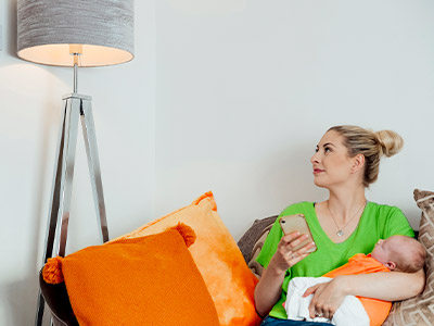 Woman in a green shirt sitting on a couch holding a child while looking up at a lamp