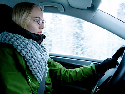 woman in a green coat driving a car