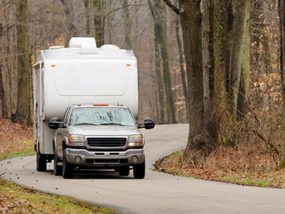 Truck pulling a camper in a wooded area