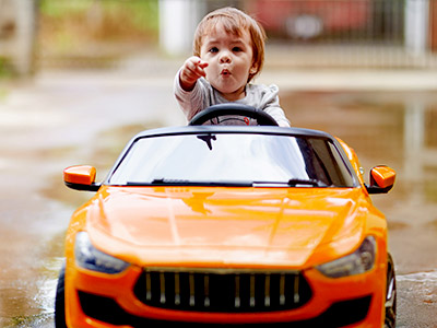 kid in an orange riding toy car