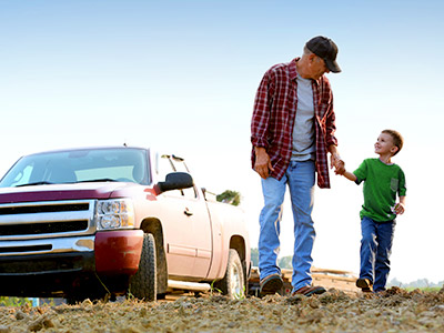 Father and son standing in a field in front of a truck