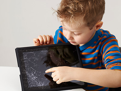 little boy pointing to a tablet with a cracked screen