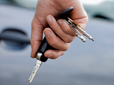 holding a car key in front of a car