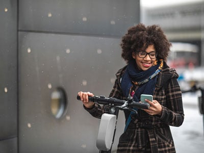 Woman on an electric bike or scooter looking at her phone