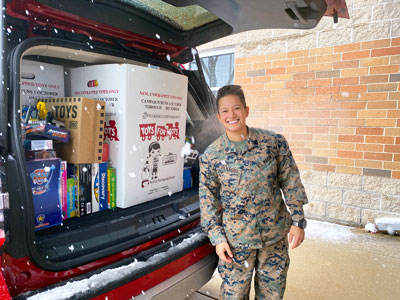 Marine Staff Sergeant Penagos standing in front of items donated to Toys for Tots