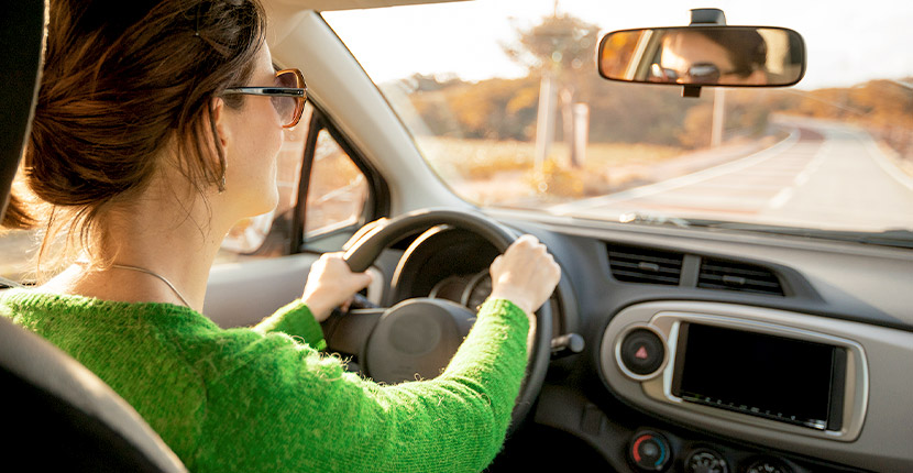 woman in green shirt driving down a road