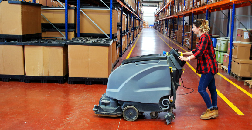 Worker pushing a floor scrubber