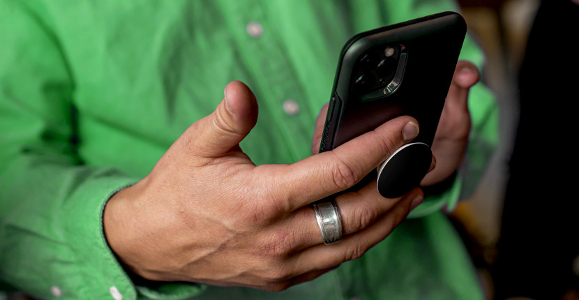 Person wearing green using a phone with a PopSocket