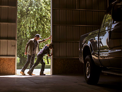 Father and Son opening garage door revealing a truck
