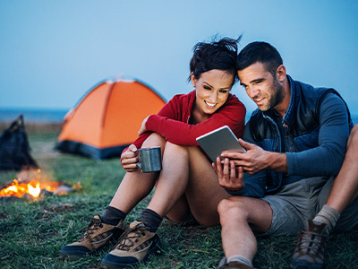 Couple camping looking at a tablet